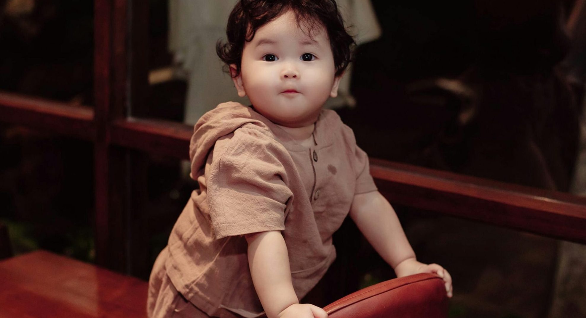 babay standing on a chair close to a window